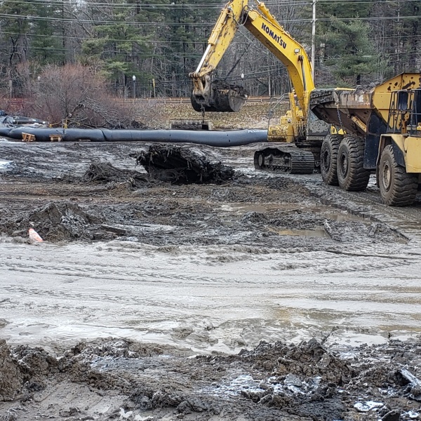 Backhoe loading sediment into dump truck